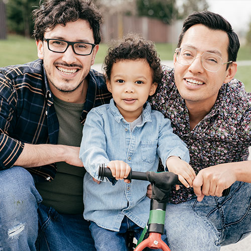 Two fathers with their child at the park